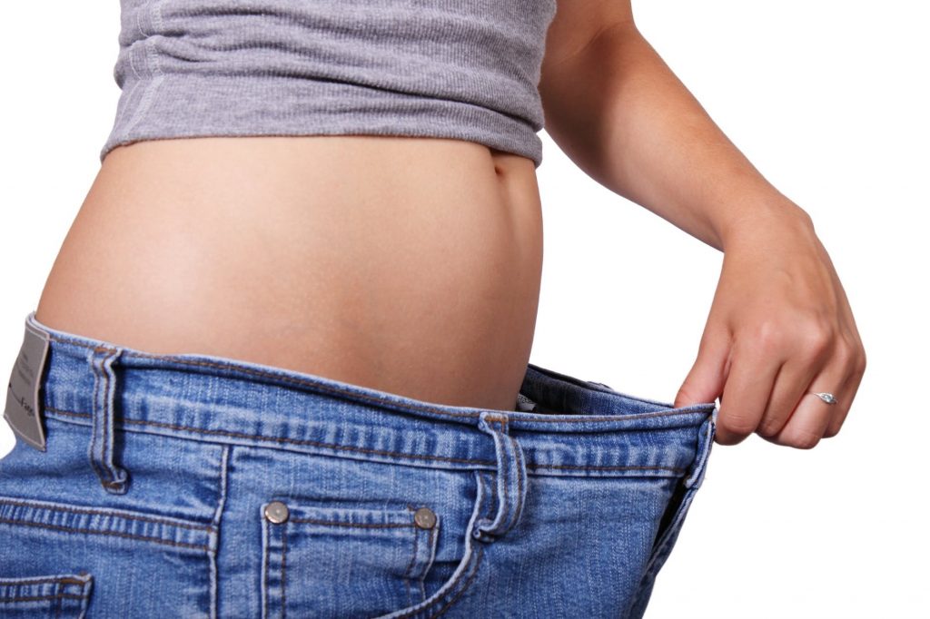 lady holding the waistline of her jeans out to show she lost weight
